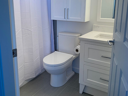 Bathroom with vinyl flooring, toilet, and white vanity