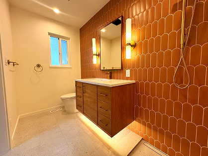 Main bathroom with patterned tile wall and wood vanity